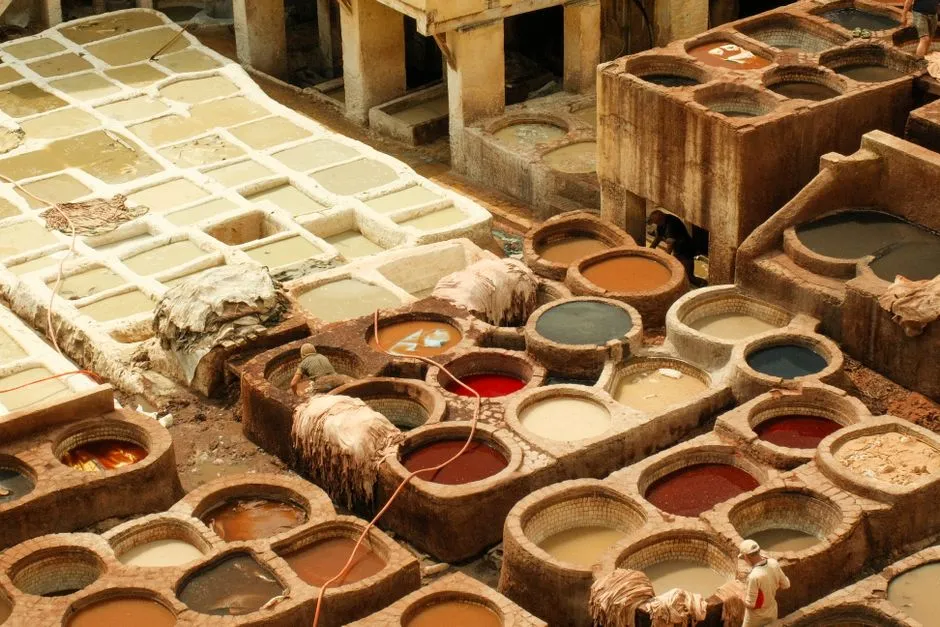Workers standing in colorful circular dyeing pits at the Chouara Tannery in Fes, Morocco